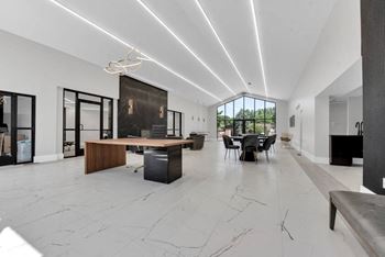 A modern office space with a long white table and black chairs.